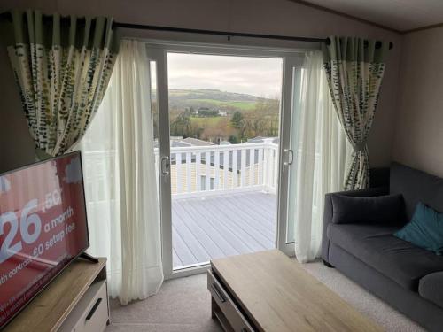 a living room with a couch and a large sliding glass door at Coastal caravan with superb view in Bembridge