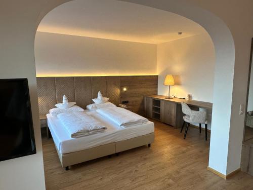 a bedroom with a large bed and a desk at Royal Hotel Hinterhuber in Brunico