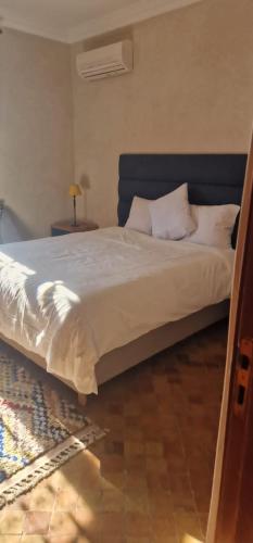 VILLA ROSERAIE في مراكش: سرير بشرشف ووسائد بيضاء في الغرفة