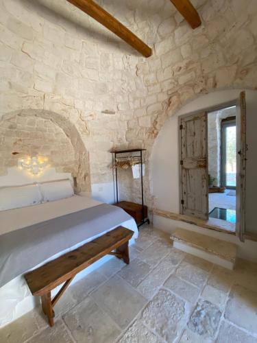 a bedroom with a bed and a stone wall at TRULLI TERRA DI MEZZO in Cisternino
