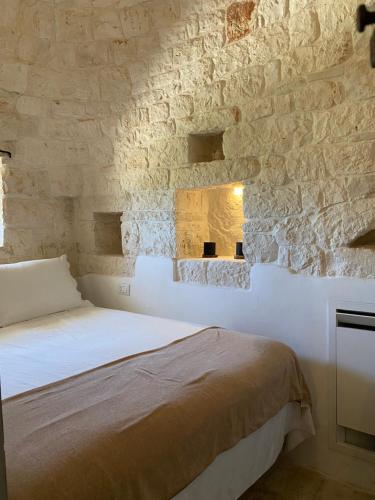 a bedroom with a bed and a stone wall at TRULLI TERRA DI MEZZO in Cisternino