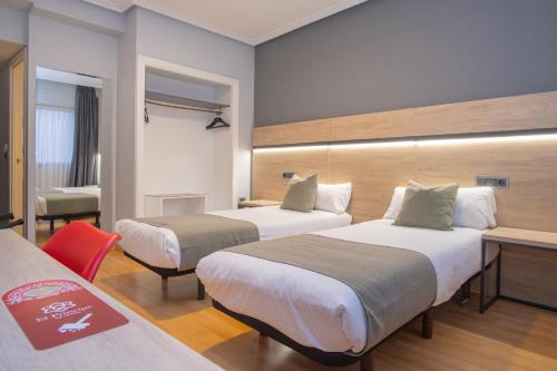 a hotel room with two beds and a desk at AZ Hotel El Príncipe in Zaragoza
