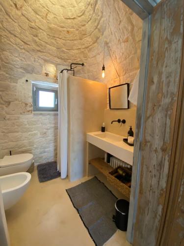 a bathroom with a white sink and a toilet at TRULLI TERRA DI MEZZO in Cisternino