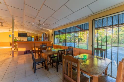 a restaurant with wooden tables and chairs and windows at Hotel El Cocobolo Food&Rest Room 3 B&B WiFi AC Pkg Free Swimmingpool in Liberia