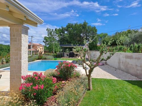 een tuin met een zwembad en bloemen bij Villa Meliora in Vižinada