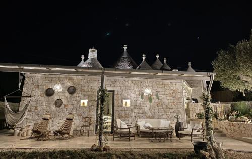 a stone building with chairs and a patio at night at TRULLI TERRA DI MEZZO in Cisternino