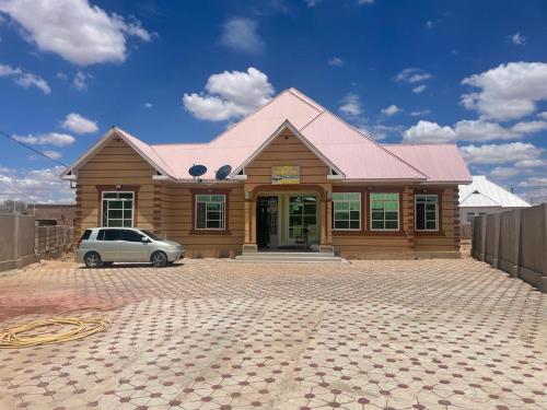 una casa con un coche aparcado delante de ella en The First Royal Tour Lodge en Dodoma