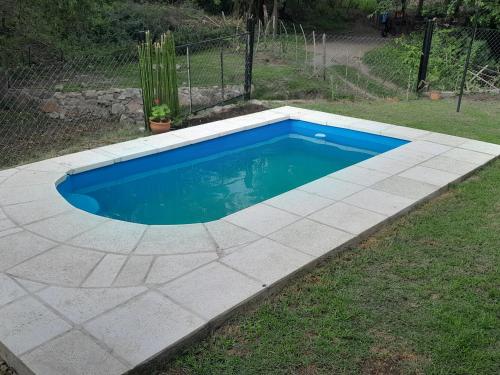 een zwembad in een tuin met een betonnen vloer bij El Rinconcito de la Selva in La Calera