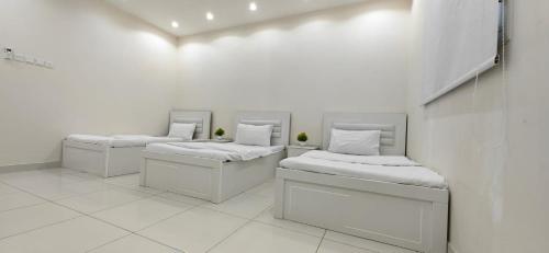 three beds in a room with white walls at اوس الحجاز in Rayyis