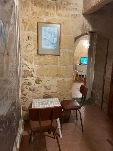 a room with two chairs and a table in a stone wall at 400YR Farmhouse in Xaghra Gozo - Entire Farmhouse in Tal-Barmil