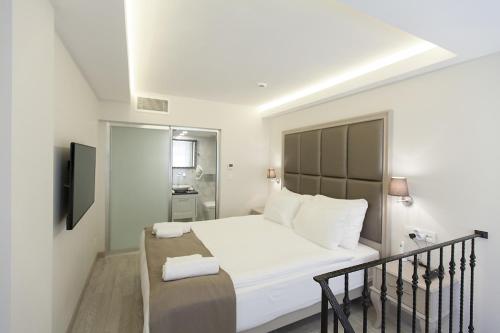a white bedroom with a bed and a balcony at Perla Galata Hotel in Istanbul