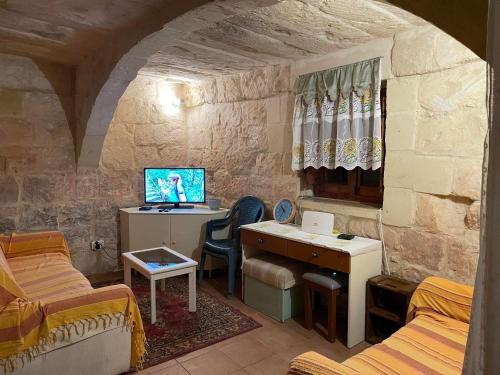 a room with a desk and a computer in a stone room at 400YR Farmhouse in Xaghra Gozo - Entire Farmhouse in Tal-Barmil