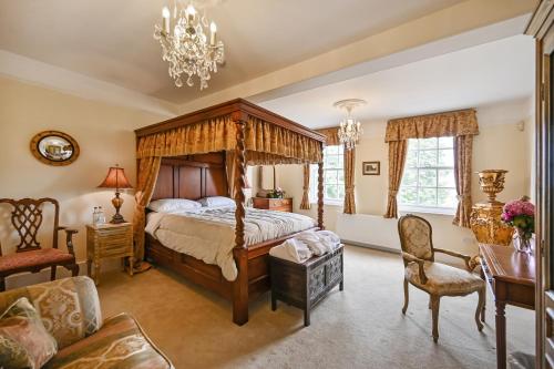 a bedroom with a canopy bed and a chair at Saltcote Place in Rye