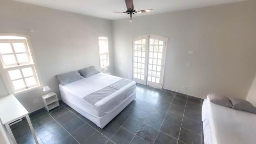 um quarto com uma cama branca e 2 janelas em Pousada Genesis Guaruja no Guarujá