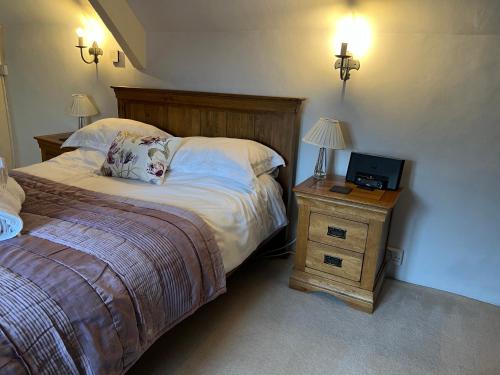 a bedroom with a bed and a night stand with a tv at Characterful, Cosy Cotswold Cottage, Folly Cottage in Avening