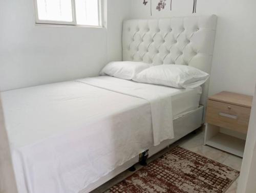 a white bed in a bedroom with a window at Apartamento central en Cali, Colombia 302 in Cali