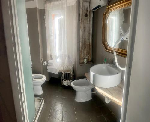 een badkamer met 2 toiletten, een wastafel en een spiegel bij le Piagge in Viterbo