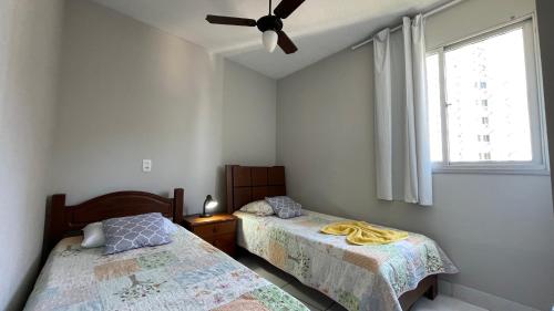 a bedroom with two beds and a ceiling fan at STropez com vista pro mar - Praia Areia Preta in Guarapari