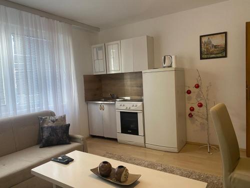 a living room with a couch and a kitchen with a refrigerator at Apartman B&B in Pale
