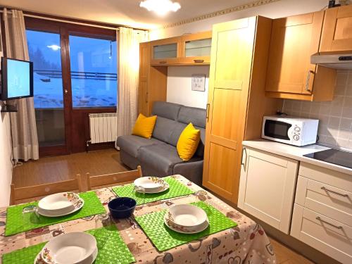 ブレウイル・チェルヴィナイアにあるFagus Cervinia apartment Vda Vacanze in Vetta CIR 0206の小さなキッチン、リビングルーム(テーブル付)が備わります。