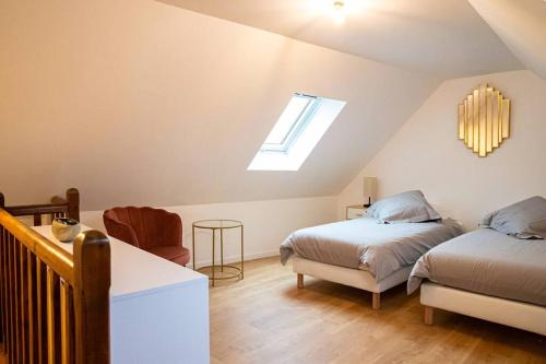 Un dormitorio abuhardillado con dos camas y una ventana. en Gîte Les Camélias 2 chambres, 2 salles de bains, en Villers-Cotterêts