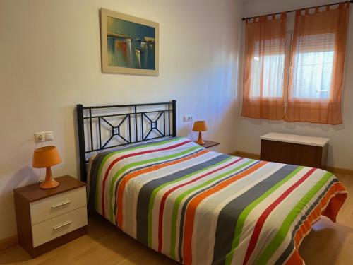 ein Schlafzimmer mit einem Bett mit einer bunten gestreiften Decke in der Unterkunft El Mirador de Ines in El Puerto de Santa María