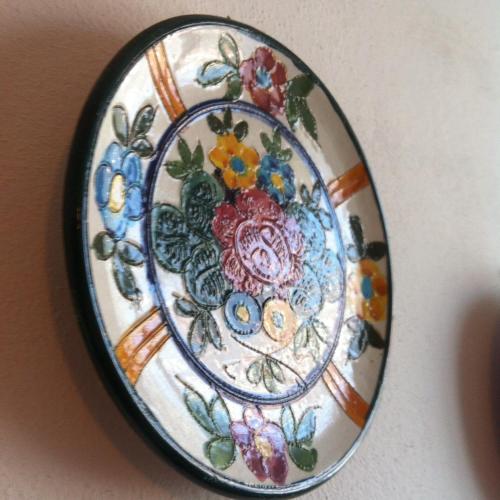 a plate with a floral pattern on a wall at Cav Costa degli Etruschi in San Vincenzo