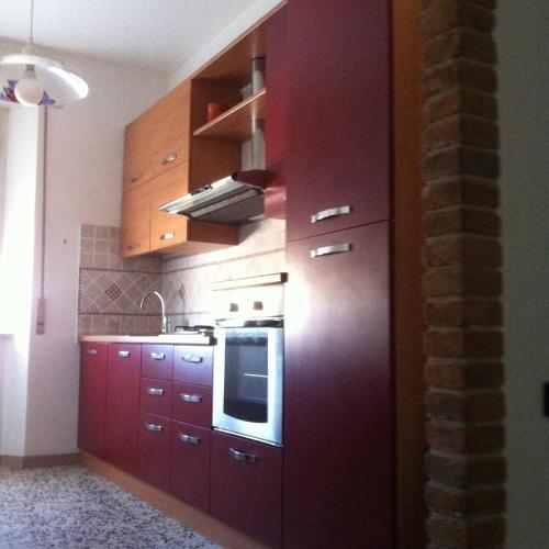 a kitchen with red cabinets and a stove top oven at Cav Costa degli Etruschi in San Vincenzo