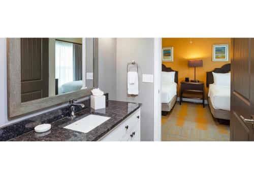 ein Badezimmer mit einem Waschbecken und ein Schlafzimmer mit 2 Betten in der Unterkunft Special Offer! Deluxe 2BR Condo Near Orlando Theme Parks - Disney World - Universal - SeaWorld - Space Center in Orlando