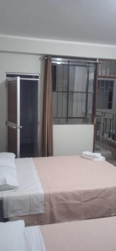 sypialnia z dużym białym łóżkiem i oknem w obiekcie Los Kristales w mieście Tingo María