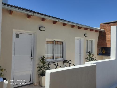 a white house with a porch with chairs on it at Gotas de Rocio in San Antonio Oeste