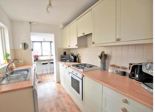 a kitchen with white cabinets and a stove top oven at Stamford - 2 bed terrace house in Lincolnshire