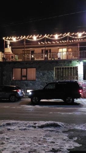 a black car parked in front of a building with lights at Come & Rest in Stepantsminda