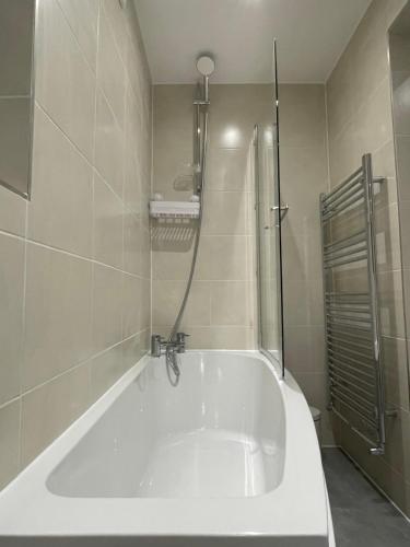 a white bath tub in a bathroom with a shower at Newly renovated flat in Ashtead in Ashtead