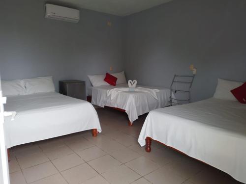 Habitación con 2 camas y una silla. en Hotel María Inés en Veracruz