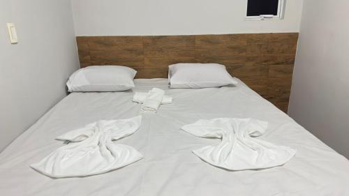 Una cama con sábanas blancas y toallas. en Suítes Tambaú, en João Pessoa