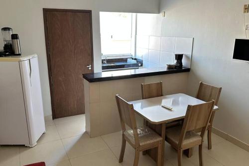 a kitchen with a white table and chairs and a counter at Apartamento frente ao mar na praia do guaibim. in Guaibim