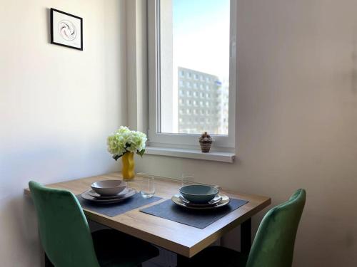 a dining room table with green chairs and a window at SkyNest B404 in Bratislava