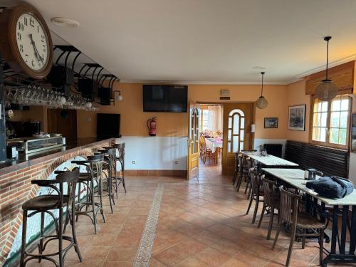 un restaurante con mesas y sillas y un reloj en la pared en Hotel Pico Espiguete, en Alba de los Cardaños