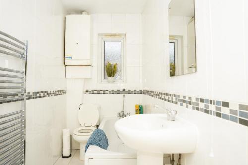 a white bathroom with a sink and a toilet at Modern Retreat Central Location Close to The City in Killingbeck
