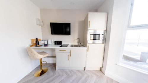 a white kitchen with a sink and a refrigerator at Bowles Hotels in Redcar