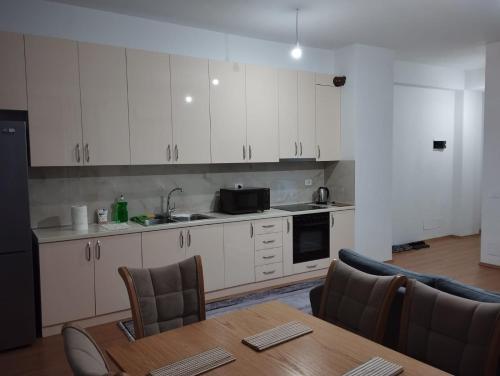a kitchen with white cabinets and a table with chairs at Alban Apartment in Tirana
