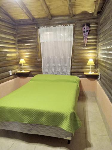 a bedroom with a green bed and two lamps at Peumayen Cabañas in Villa Las Rosas