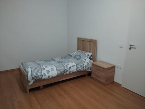 a bedroom with a bed and a wooden night stand at Alban Apartment in Tirana