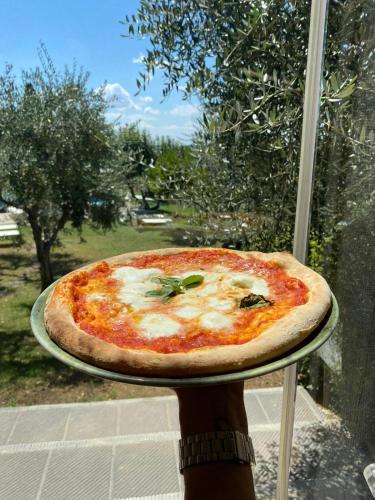 a person holding a pizza on a tray at Tenuta Massabò in San Casciano in Val di Pesa