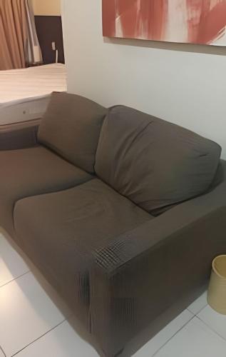 a brown couch sitting in a living room at Studio pé na areia, vista, internet e ar in Macaé