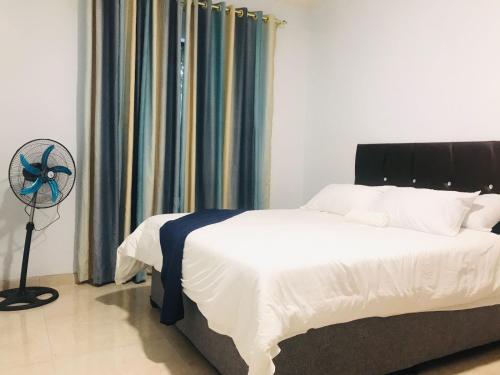 a bedroom with a bed and a fan next to a window at KaMageba Palace in Durban