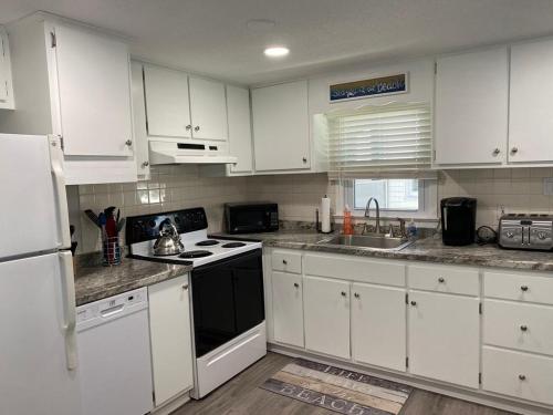 uma cozinha com armários brancos e um forno de fogão preto em Newly Renovated Ocean Block Duplex Located In The Heart Of Surf City, em Surf City