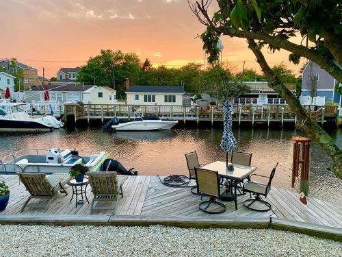 a wooden dock with a table and chairs and a boat at Rental Available For Your Vacation Pleasure, All The Comforts You Could Imagine, Great Location! in Manahawkin