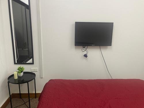 1 dormitorio con 1 cama y TV de pantalla plana en la pared en Hostal EntreOrientes en Viña del Mar